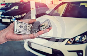 Businessman purchase new car in showroom giving dollars money and taking keys from car