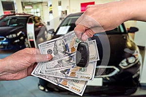 Businessman purchase new car in showroom giving dollars money and taking keys from car