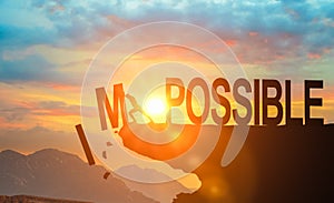 Businessman push impossible wording to possible wording on top of mountain with bright sunset sky. Positive mindset concept
