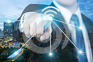 Businessman push wifi icon on city and network connection concept. Bangkok smart city and wireless communication network, abstract