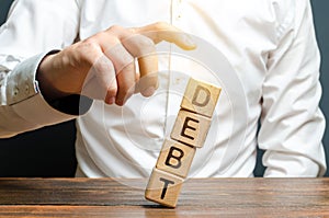 A businessman pushes down a tower of cubes with the word Debt. concept of financial relief, loan restructuring. Financial