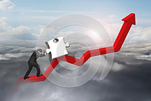 Businessman pushing 3D jigsaw puzzle upward on red trend line