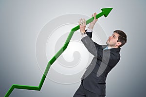Businessman is pushing arrow in graph up. Growth and maximizing earnings concept photo