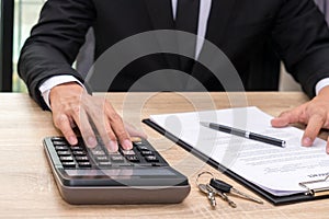 Businessman pushing calculator on wooden desk - buy home concept