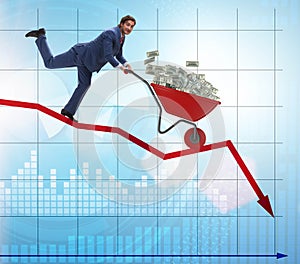 Businessman pushing money wheelbarrow down the chart