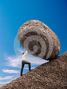 Businessman pushing up boulder photo