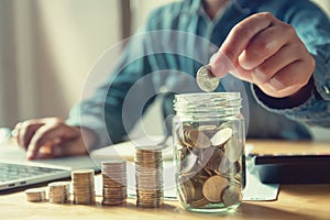 businessman puting coins into jug glass. concept saving money an