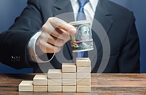 Businessman puts a dollars bundle on top of stairs. Raising bids, increase interest rate deposit account growth. Salary growth and