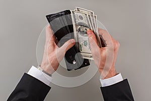 Businessman puts money to the wallet.
