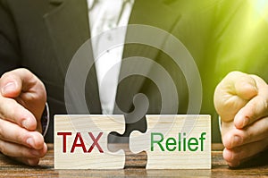 A businessman puts two puzzles with the words Tax and Relief. The concept of reducing the debt burden on business and local