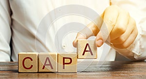 Businessman puts wooden blocks with the word CAPA. Corrective and Preventive action plans. Business management concept. Strategy photo
