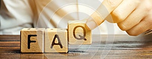 Businessman puts wooden blocks with the word FAQ frequently asked questions. Collection of frequently asked questions on any photo