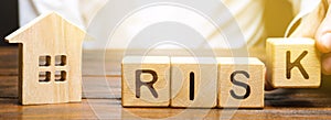 Businessman puts wooden blocks with the word Risk and a house. Real estate investment risk. Risky investments. Loss of property photo