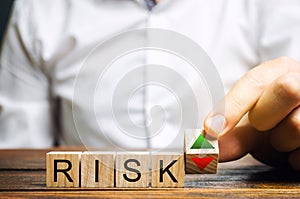 Businessman puts wooden blocks with the word Risk and up and down arrows. Business risk management concept. Forecasting and