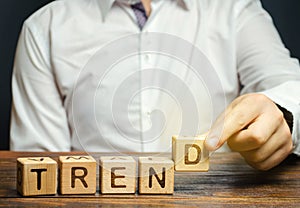 Businessman puts wooden blocks with the word Trend. Popular and relevant topics. New ideological trends. Recent and latest trend.