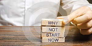 Businessman puts wooden blocks with the words Why not start now. Motivation, inspiration concept. Achievements of goals