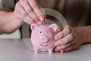Businessman putting coin into small piggy bank