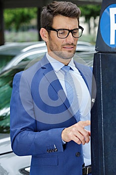 businessman putting coins in parking meter