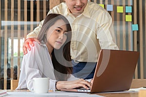 Businessman putting hand on the shoulder of female employee in office at work. She unhappy and feeling displeased with