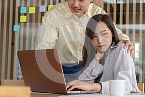 Businessman putting hand on the shoulder of female employee in office at work. She unhappy and feeling displeased with inappropria