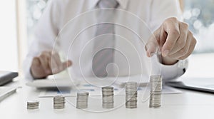 Businessman putting money on stacking coin that shows a graph the financial growth profit of business investment