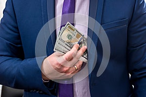 Businessman putting us money into suit pocket