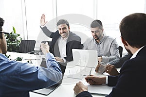 Businessman raising hand and asking question at meeting