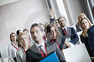 Businessman raising hand during seminar at convention center