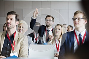 Businessman raising hand during seminar at convention center