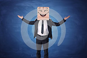 Businessman raising hands up and wearing box on his head with laughing face painted