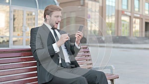 Businessman Reacting to Online Failure via Smartphone while Sitting Outdoor