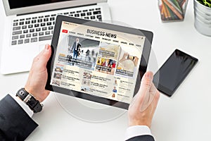 Businessman reading business news on tablet. All contents are made up. photo