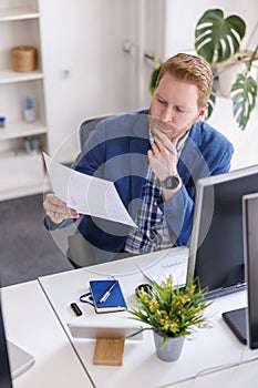 Businessman reading contracts while working in an office