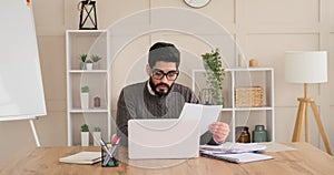 Businessman reading document and discussing while doing video conferencing on laptop