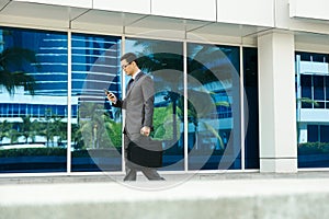 Businessman Reading Email On Mobile Phone Walking To Office