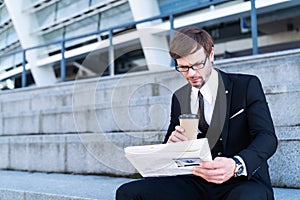 Businessman reading finance news in newspaper with coffee