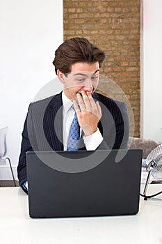 Businessman reading his laptop with a snigger