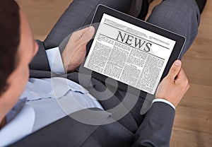 Businessman reading news on digital tablet in office