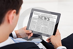 Businessman reading news on digital tablet in office