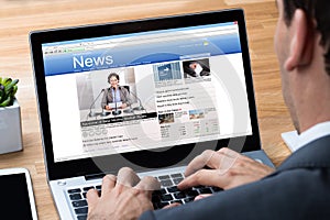 Businessman Reading News On Laptop At Desk