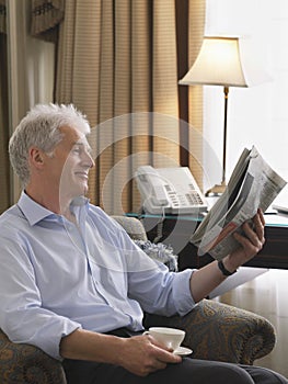 Businessman Reading Newspaper In Armchair