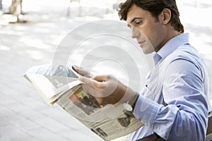 Businessman Reading Newspaper On Bench