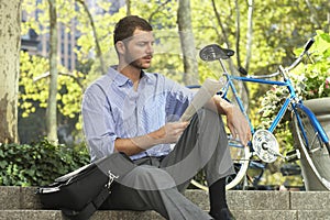 Businessman Reading Newspaper By Bicycle