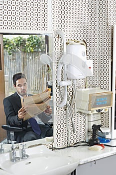Businessman Reading Newspaper In Hair Salon