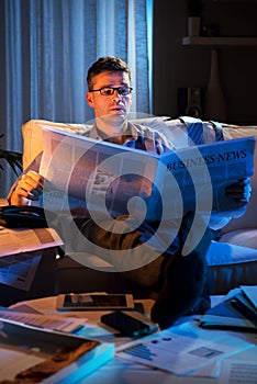 Businessman reading newspaper late at night