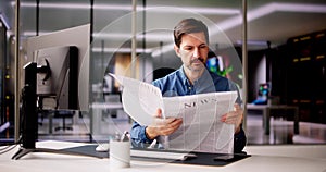 Businessman Reading Newspaper At Office Desk