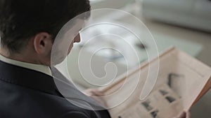 The businessman is reading the newspaper in the vip lounge hall in the airport