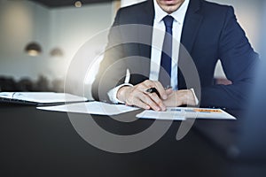 Businessman reading paperwork while sitting at his office desk