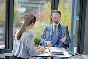 Businessman reading report of his financial advisor while sitting near window