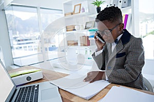 Businessman reading report while talking on phone